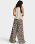 Woman wearing a patterned top and leopard print pants on a white background