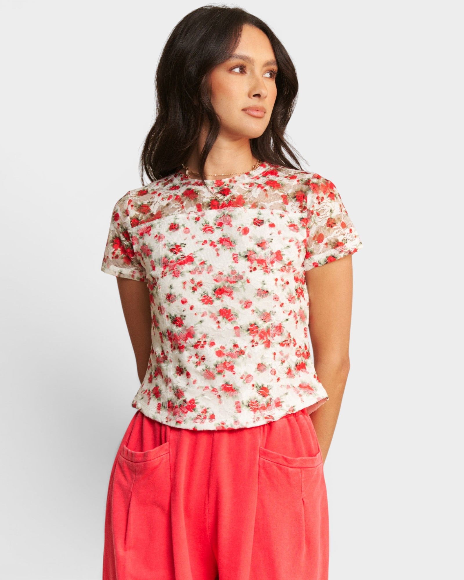 Woman wearing a floral top and red pants on a white background