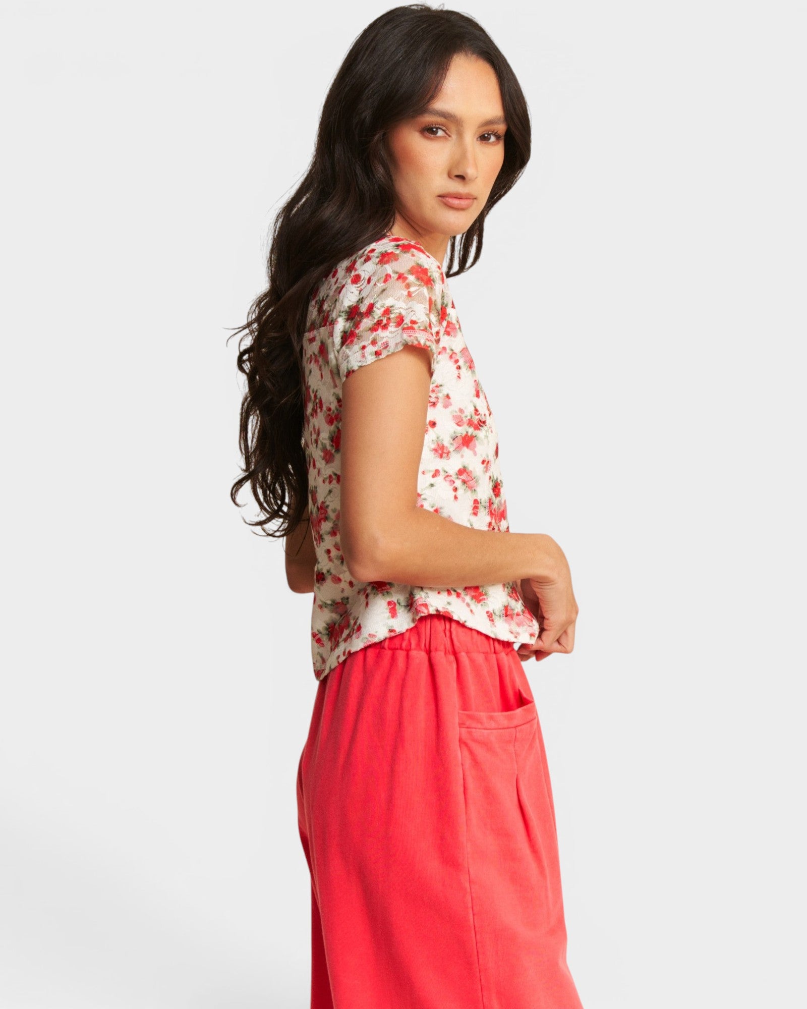 Woman wearing a floral top and red pants on a white background