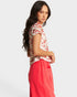 Woman wearing a floral top and red pants on a white background
