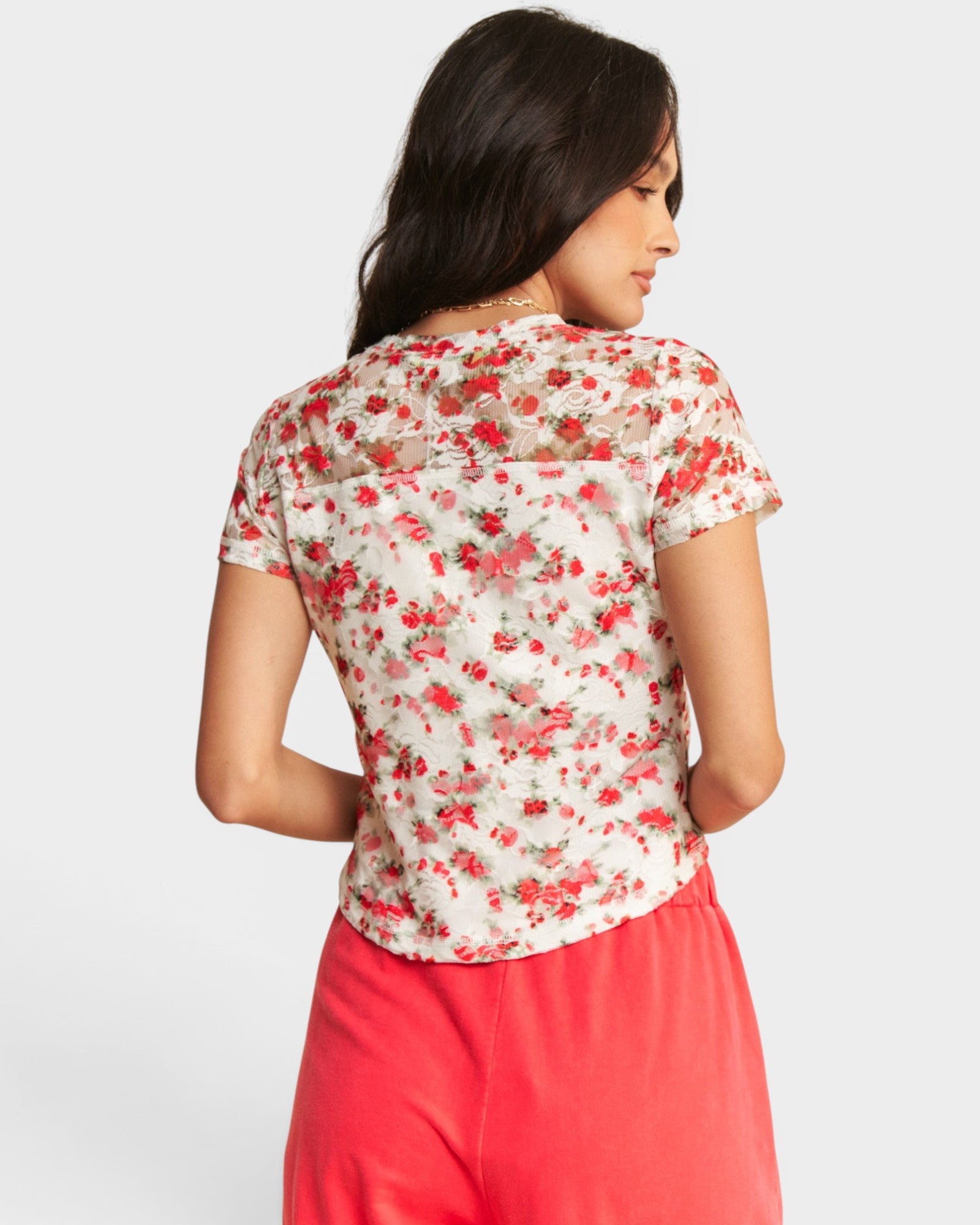 Woman wearing a floral blouse and pink pants on a white background