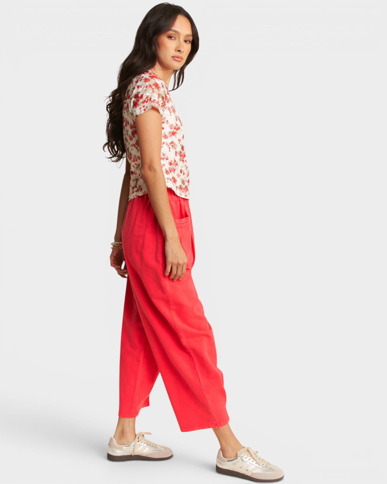 Woman wearing a floral top and red pants on a white background