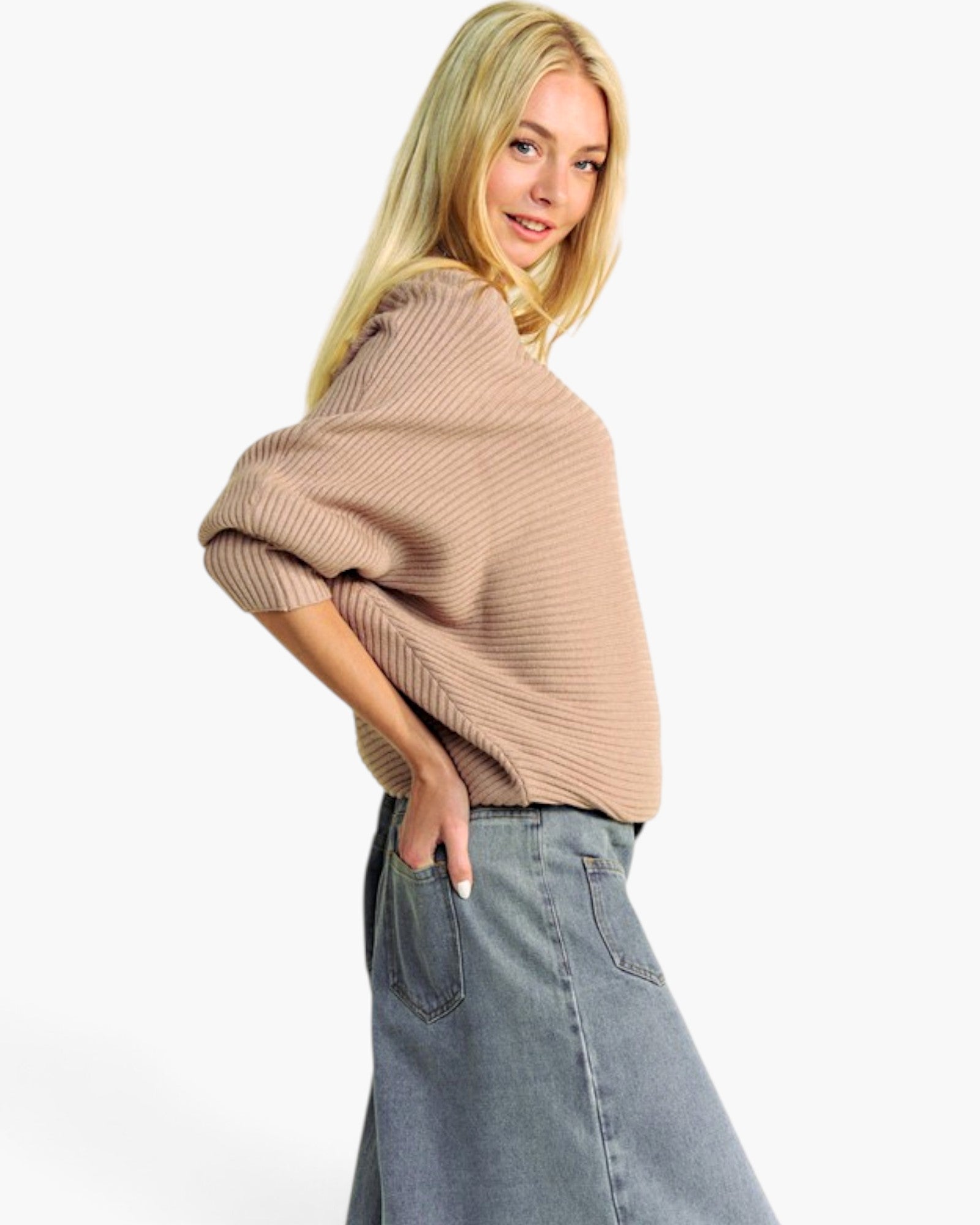 A blonde model wearing a beige ribbed knit sweater and a blue denim skirt, photographed against a clean white studio background.