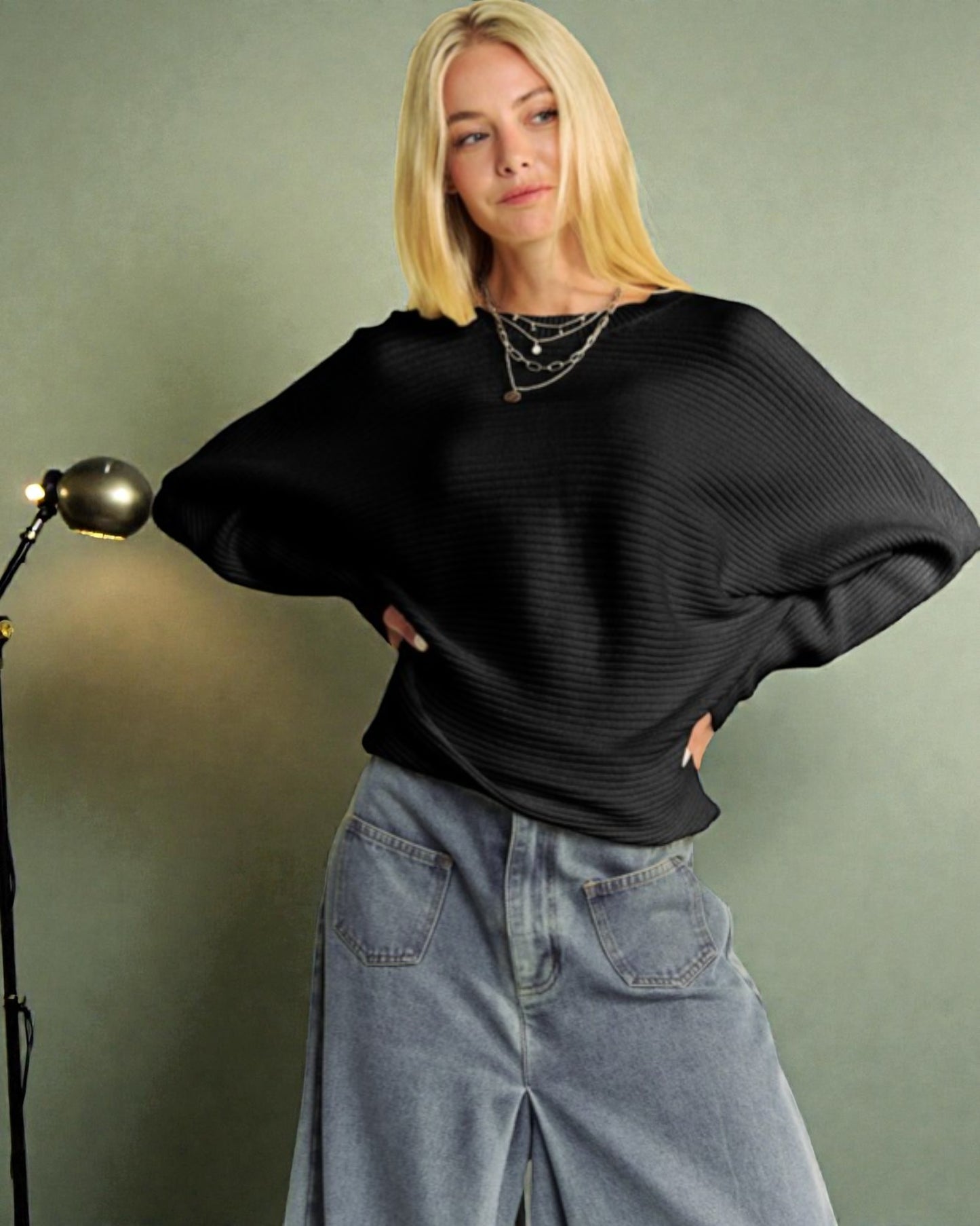 Person wearing a black sweater and blue jeans against a plain background