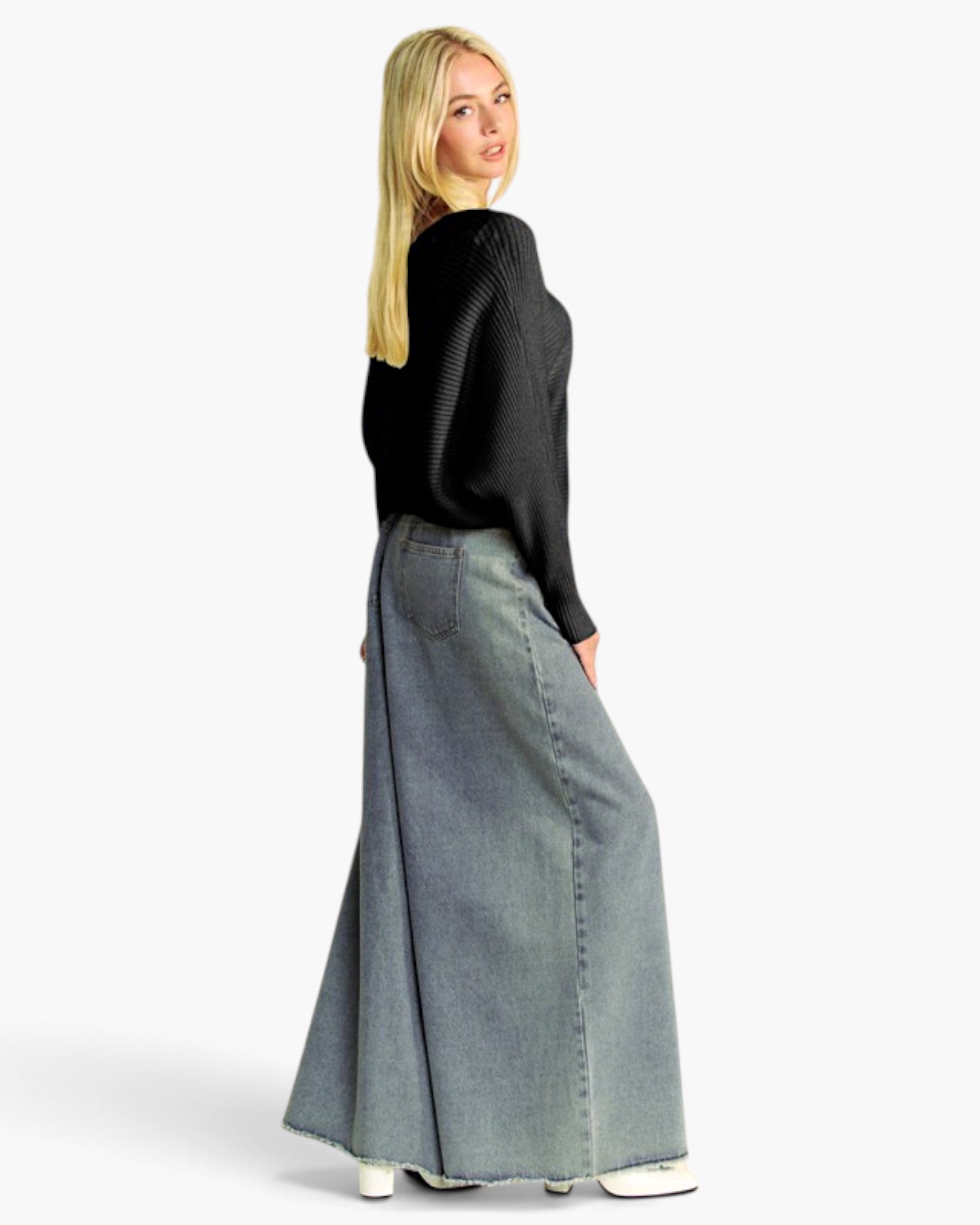 A woman wearing a black knit long-sleeve top and a wide-leg light blue denim skirt, photographed from the back against a plain white studio background.