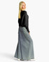 A woman wearing a black knit long-sleeve top and a wide-leg light blue denim skirt, photographed from the back against a plain white studio background.