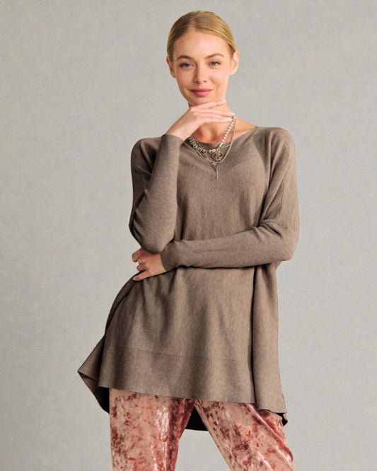 Woman wearing a brown long-sleeve top and patterned pants against a gray background