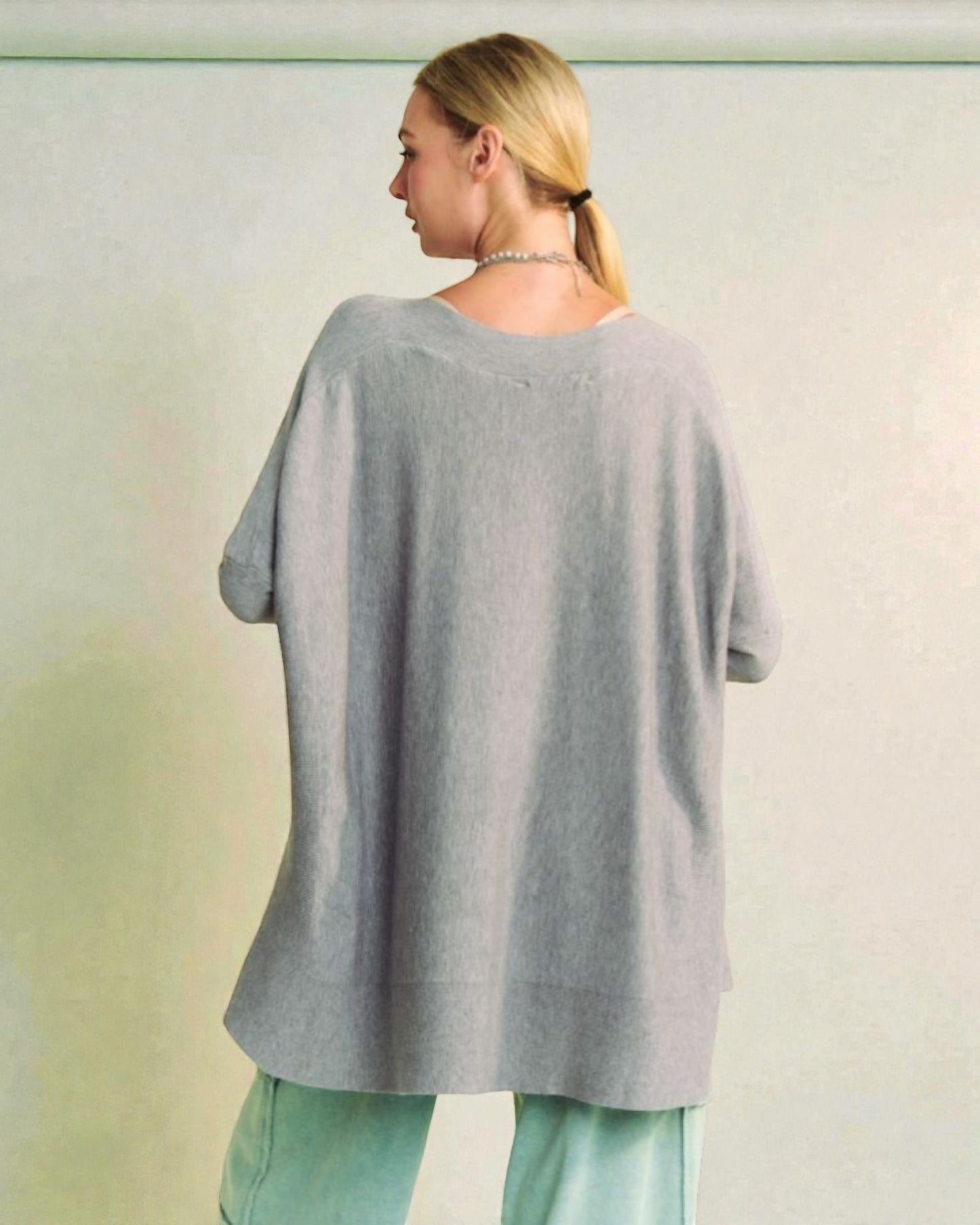 Woman wearing a gray oversized sweater with a blurred background