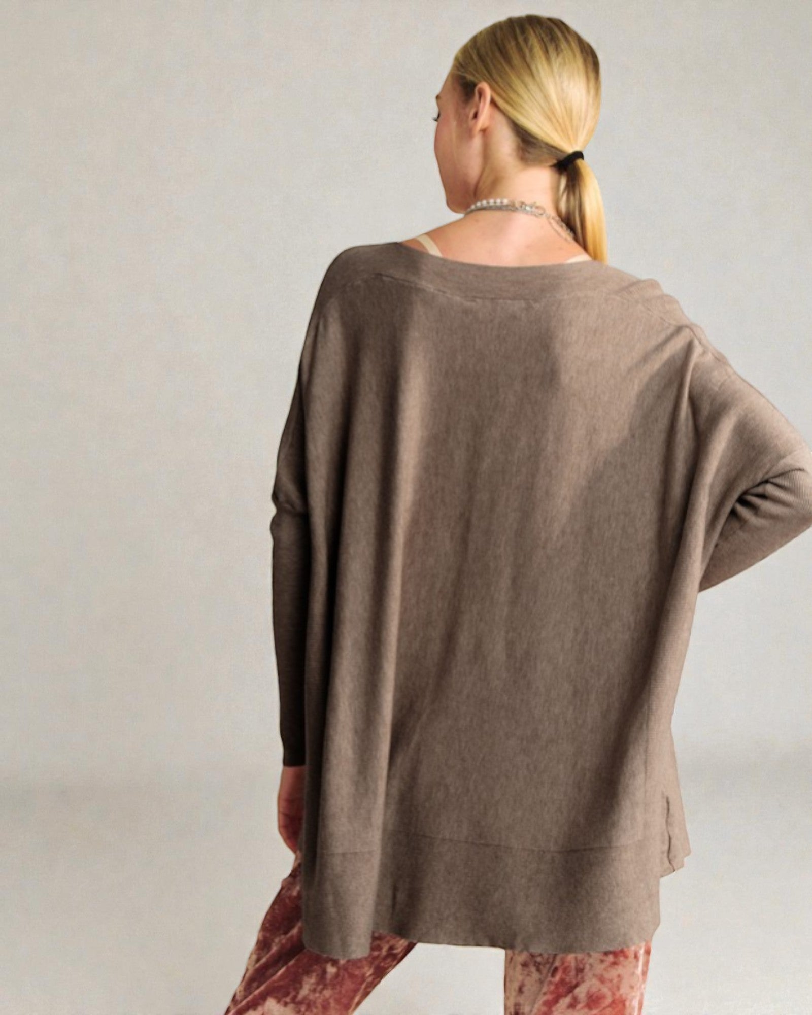 Woman wearing a brown oversized sweater against a plain background