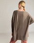 Woman wearing a brown oversized sweater against a plain background
