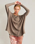 Woman wearing a brown sweater and pink pants against a plain background