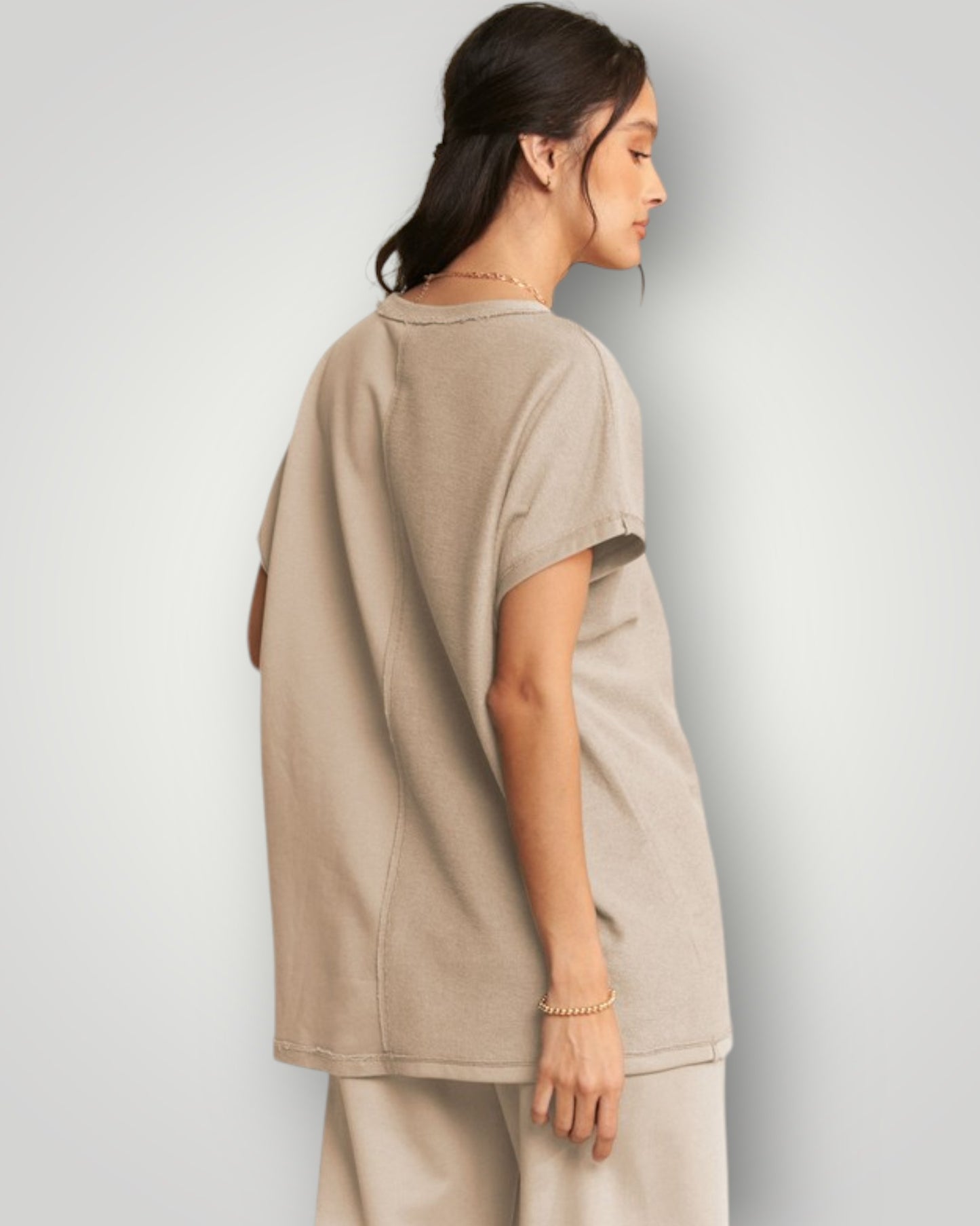 Woman wearing a beige oversized t-shirt and pants against a plain background