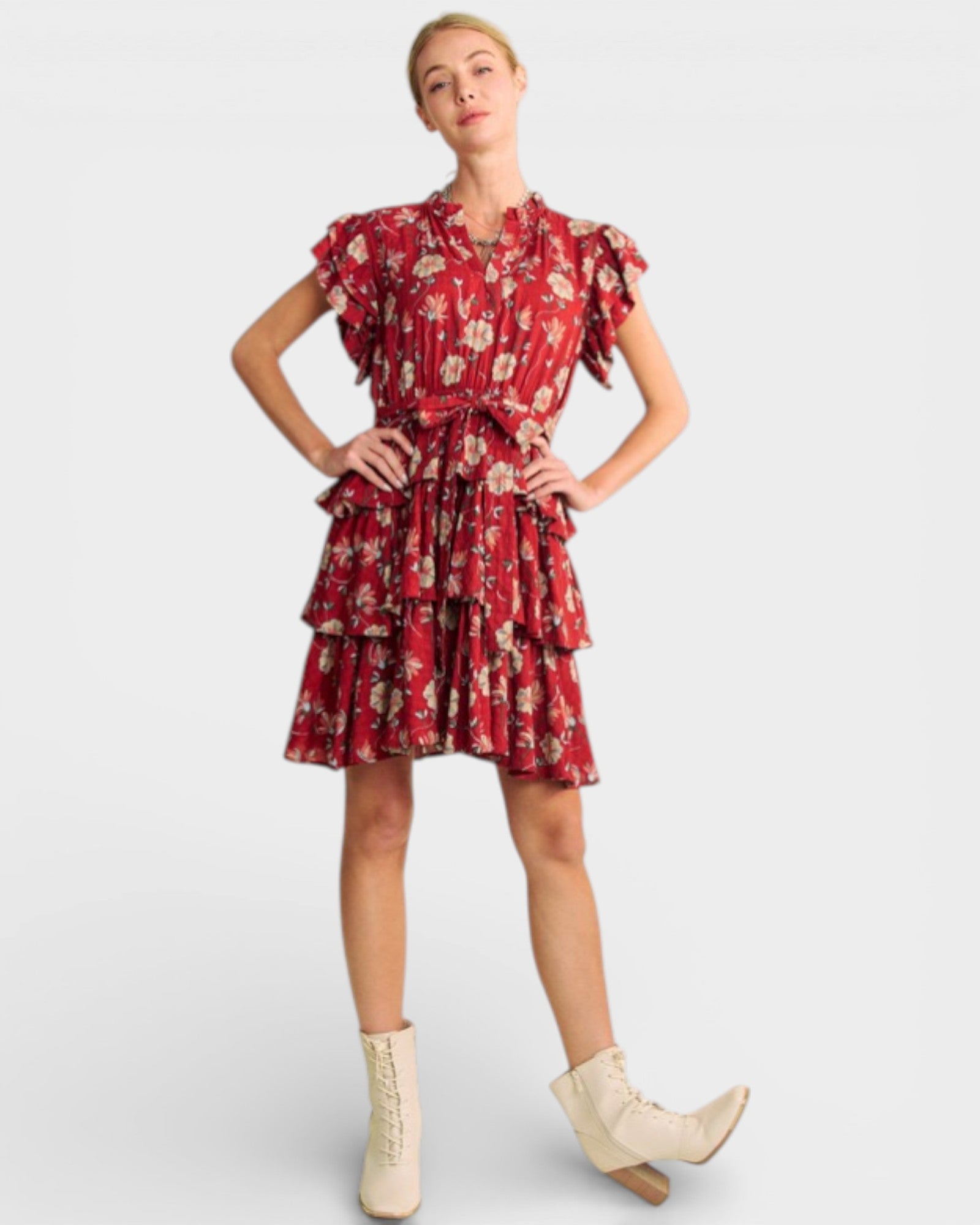 Woman wearing a red floral dress with white boots on a light gray background