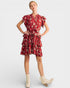 Woman wearing a red floral dress with white boots on a light gray background