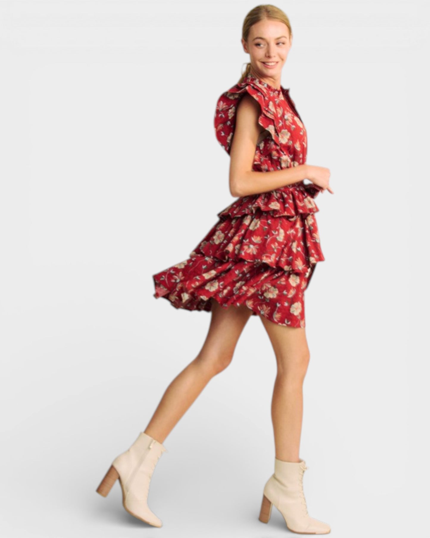 Woman wearing a red floral dress with beige boots on a white background