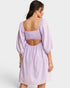 Woman wearing a light purple dress with cut-out back on a white background