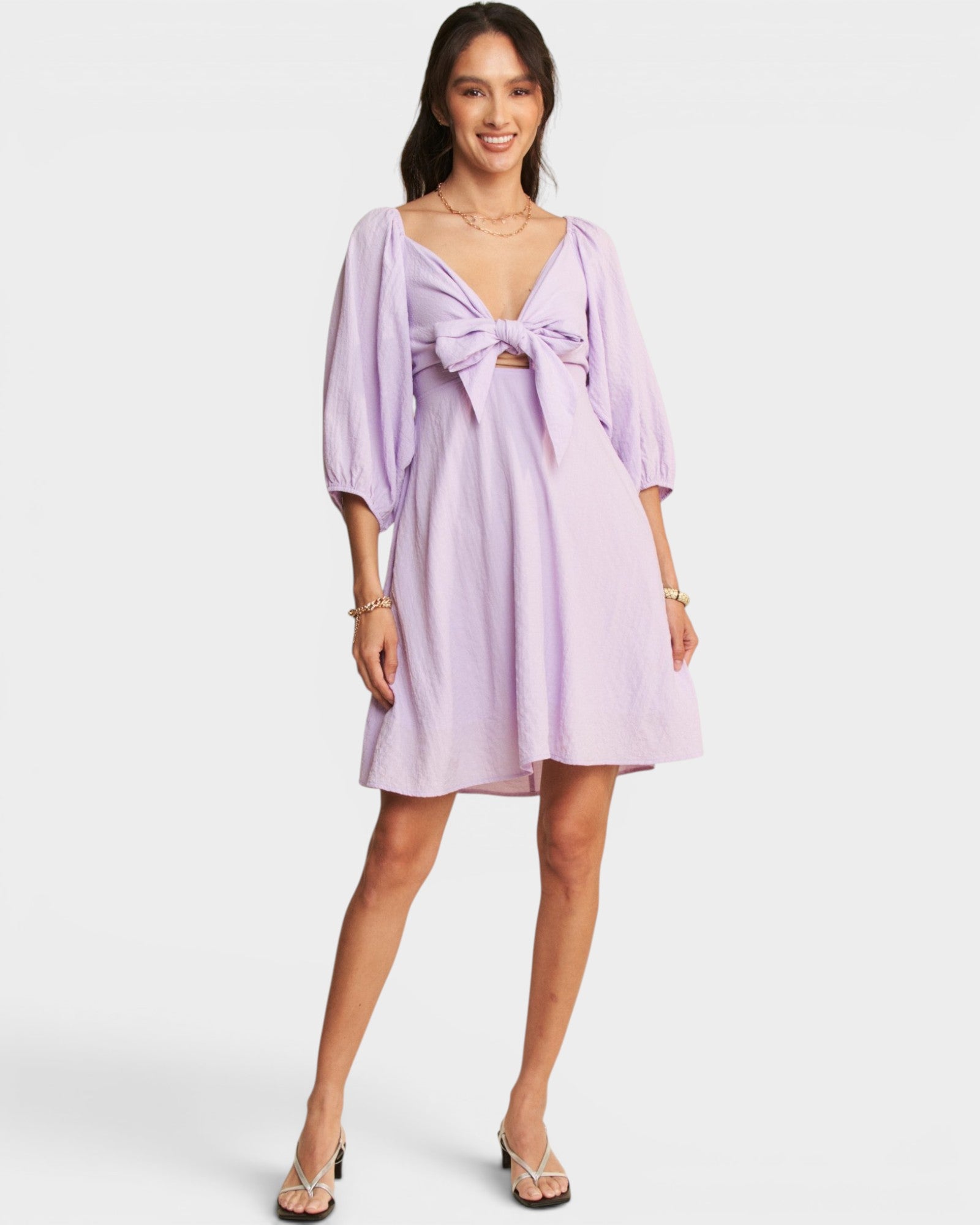 Woman wearing a light purple dress with a bow detail on a white background