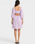 Woman wearing a light purple dress with cut-out back on a white background