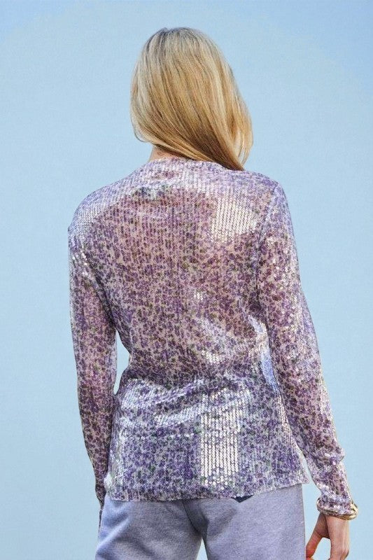 Person wearing a sparkling sequin jacket against a clear blue sky