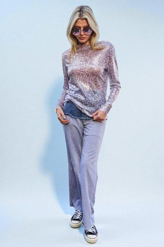 Person wearing a sparkly top and gray pants with black and white sneakers on a light blue background