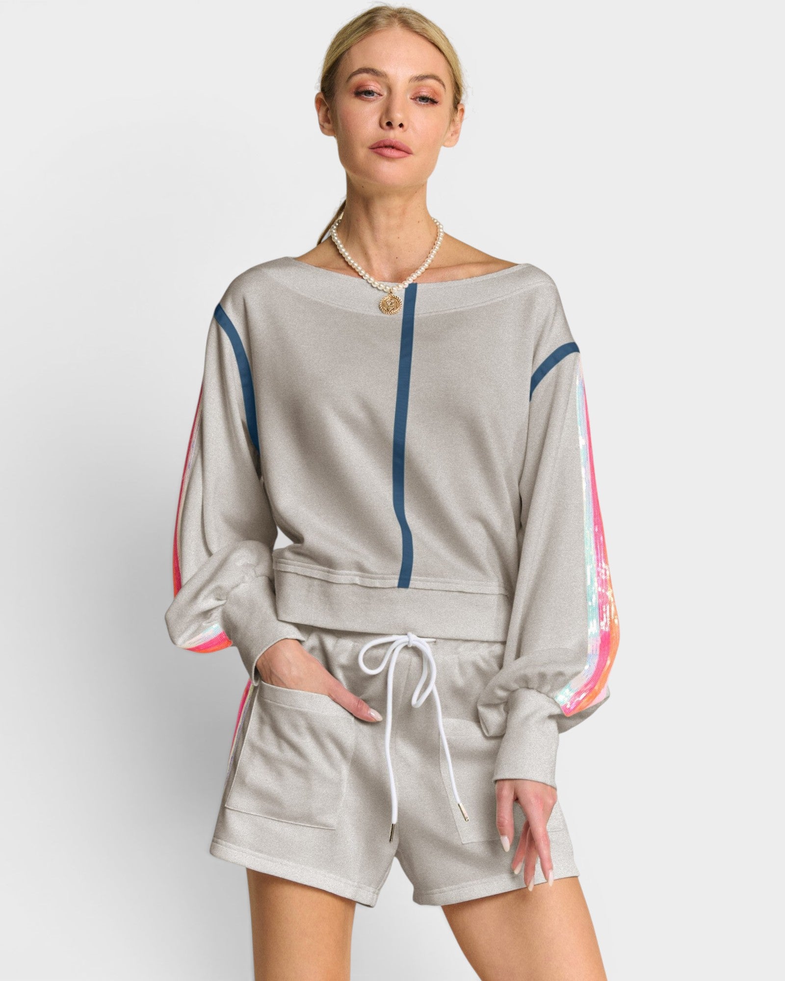 Woman wearing a gray tracksuit with colorful side panels on a light gray background