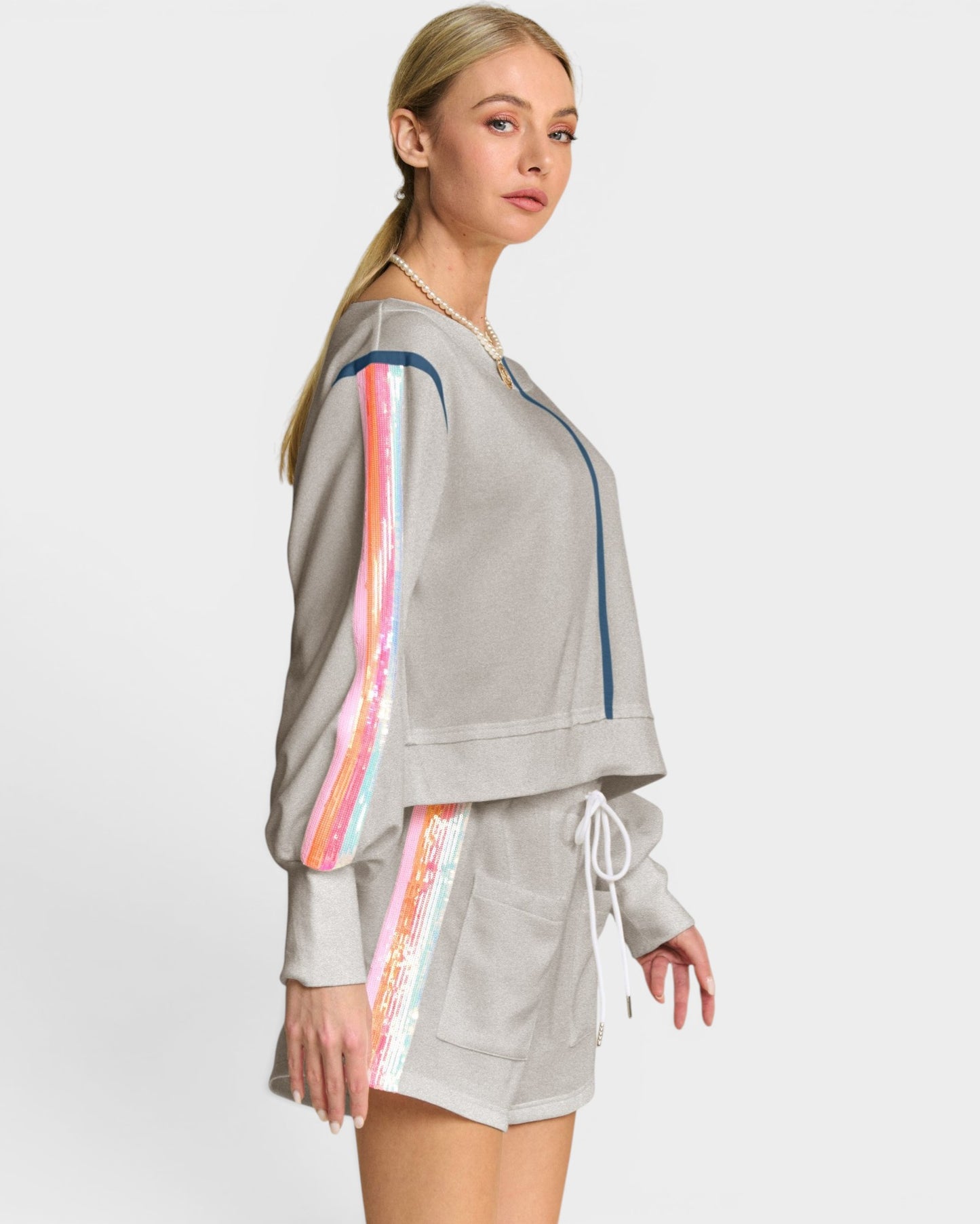 Woman wearing a gray tracksuit with colorful side panels on a white background