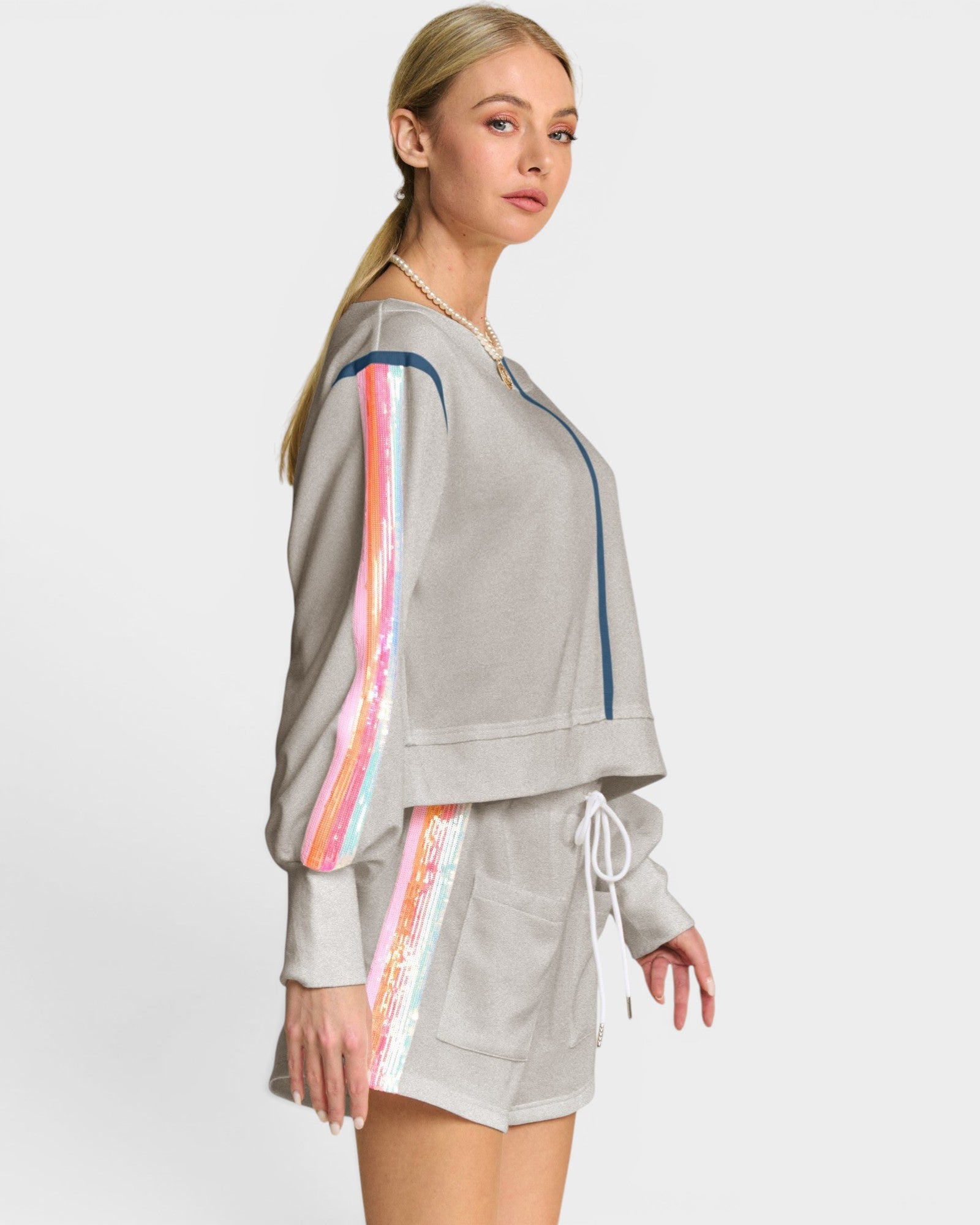 Woman wearing a gray tracksuit with colorful side panels on a white background