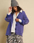Woman wearing a blue cardigan, white shirt, and leopard print pants against a beige background