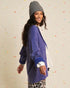 Woman wearing a blue cardigan and gray beanie against a colorful background