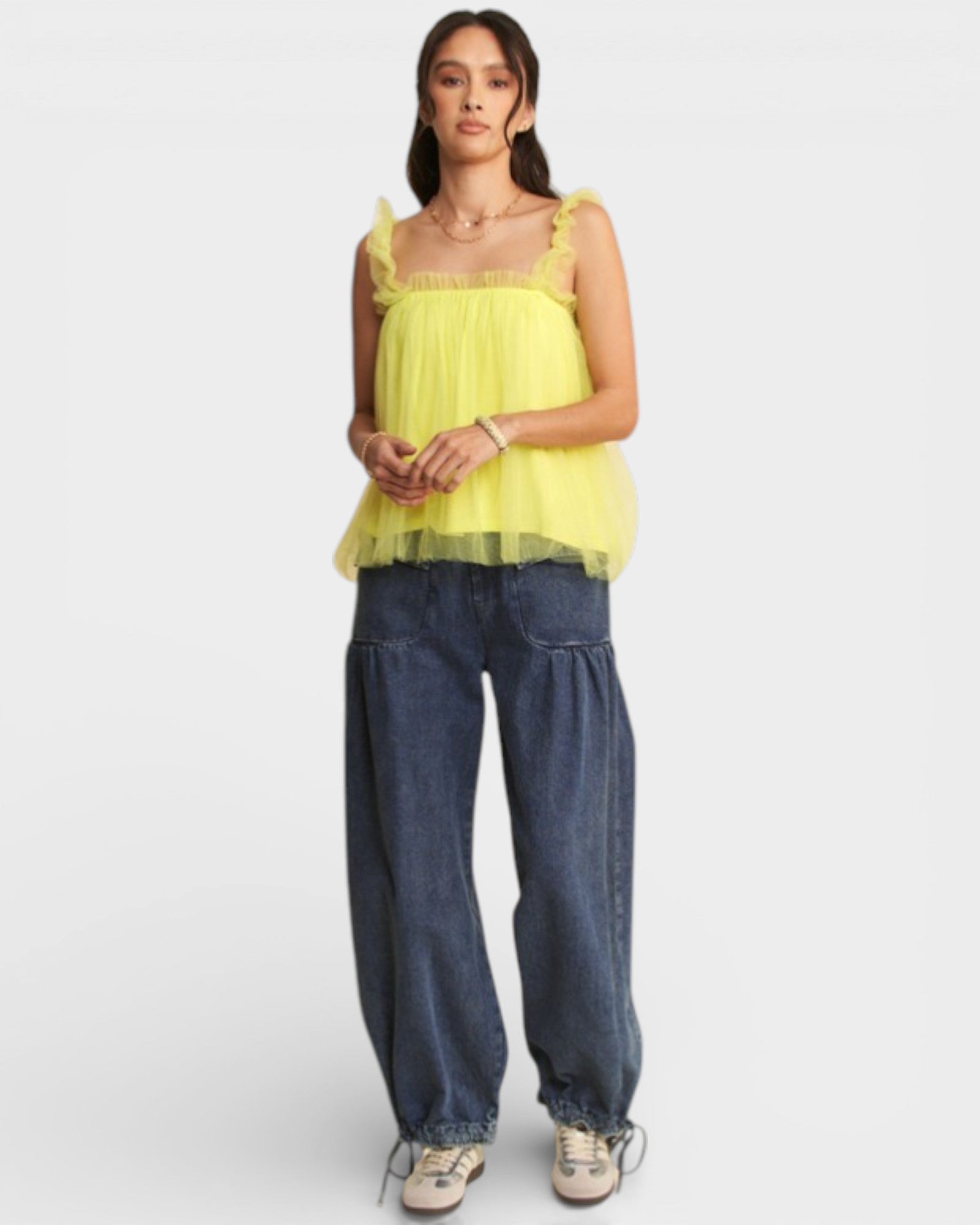 Woman wearing a yellow top and blue jeans on a white background