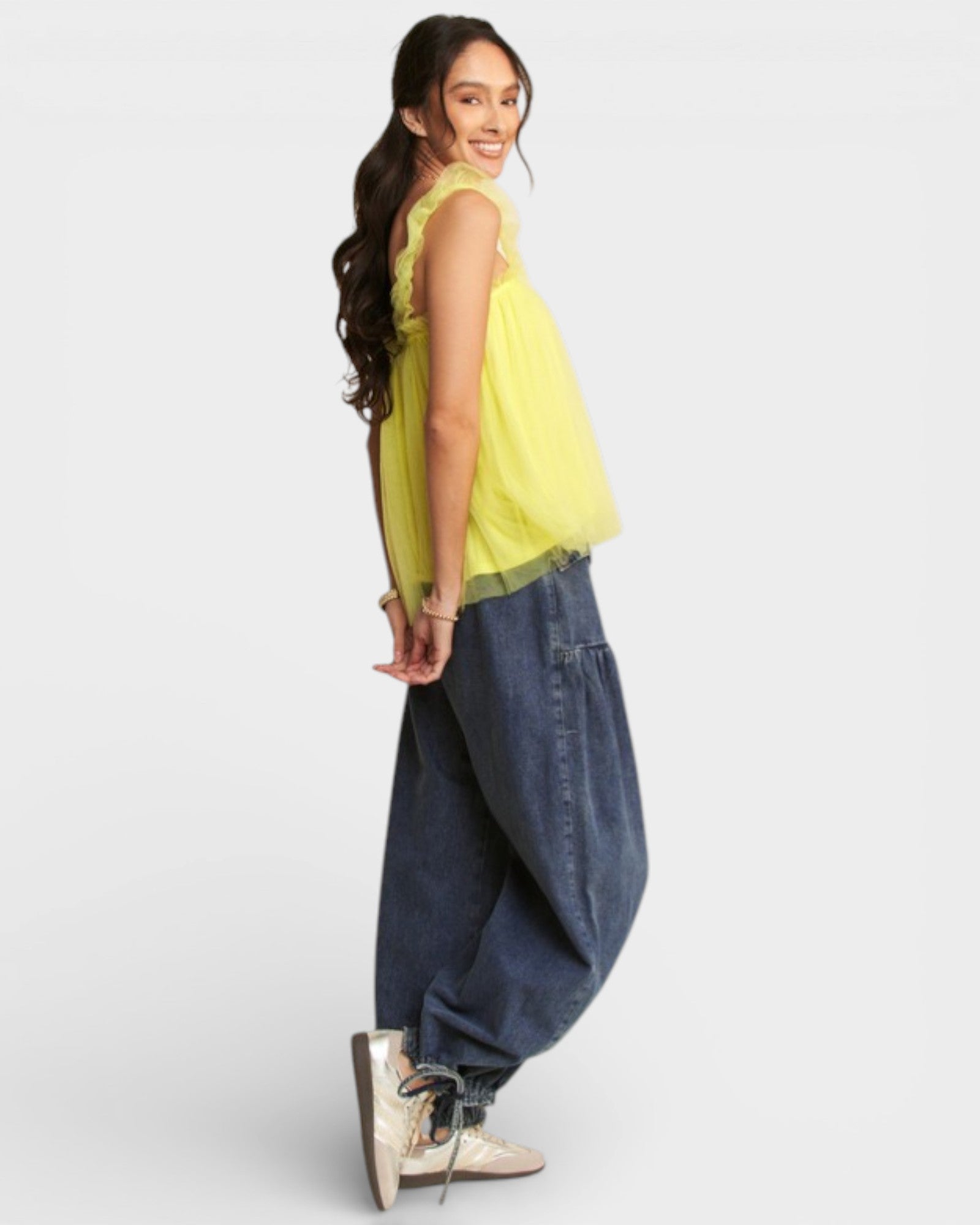 Woman wearing a yellow top and blue jeans on a white background