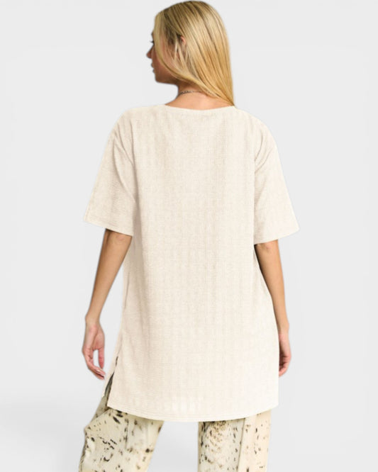 Woman wearing a beige oversized shirt with a plain background