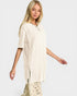 Woman wearing a beige oversized shirt with a plain background