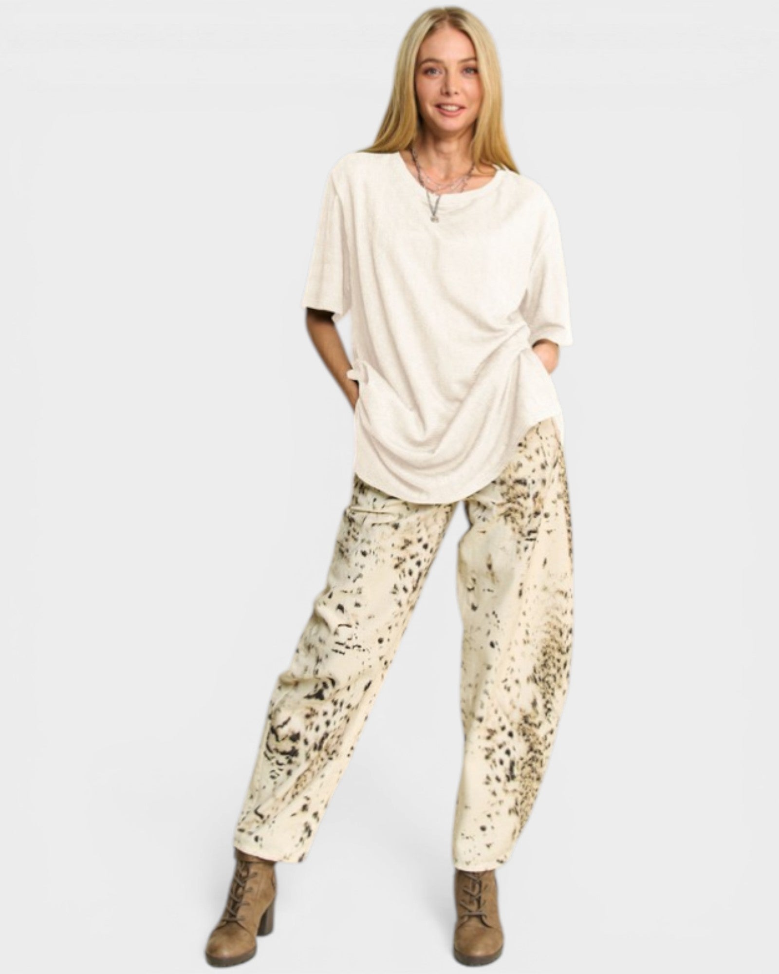 Woman wearing a cream-colored top and patterned pants on a white background