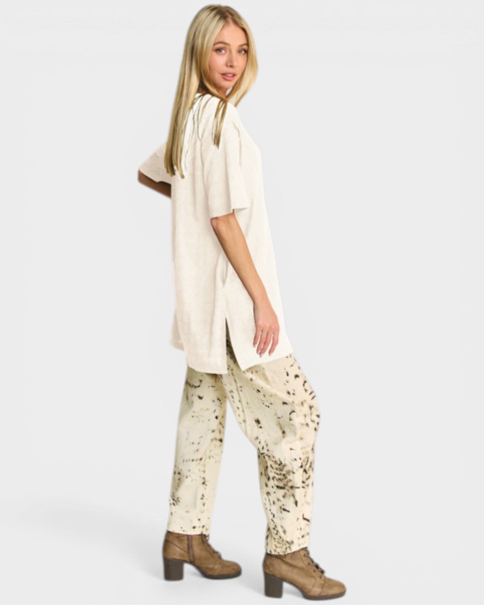 Woman wearing a beige long shirt and patterned pants on a white background