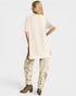 Woman wearing a beige tunic and patterned pants on a white background
