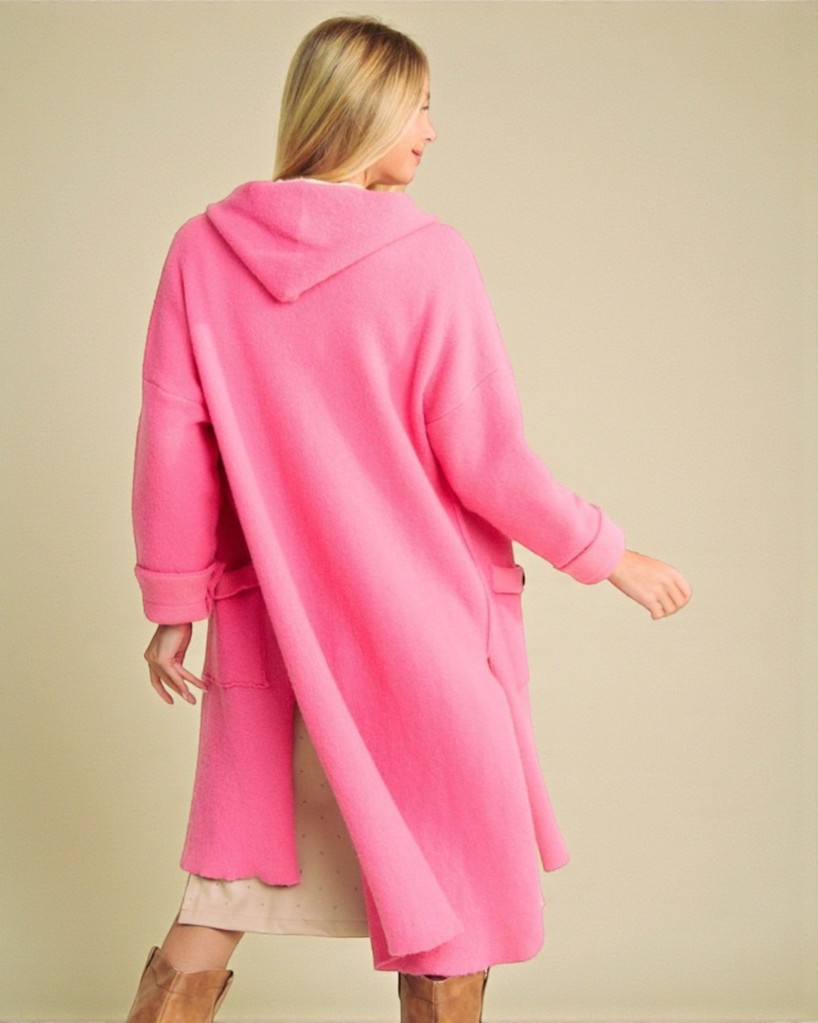 Woman wearing a bright pink coat against a beige background