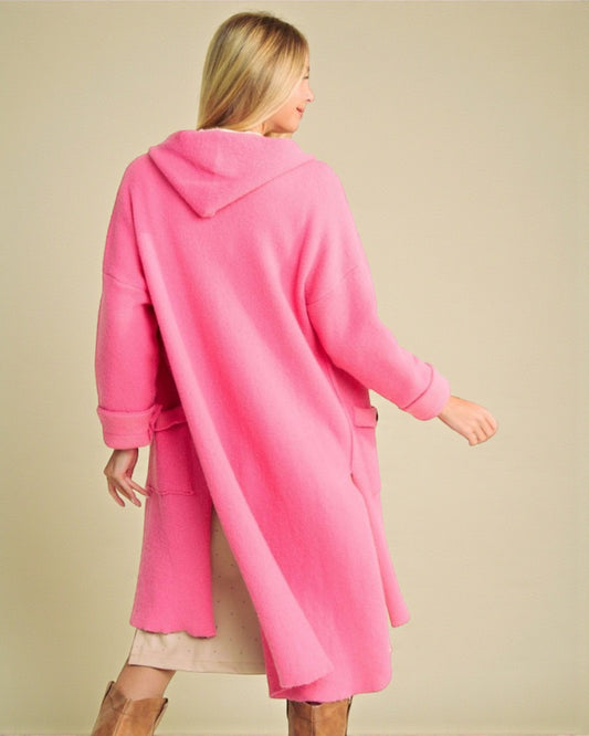 Woman wearing a bright pink coat against a beige background