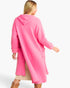 A woman wearing a bright pink hooded coat, shown from the back and side against a plain light gray studio background.