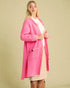 Woman wearing a pink coat against a beige background