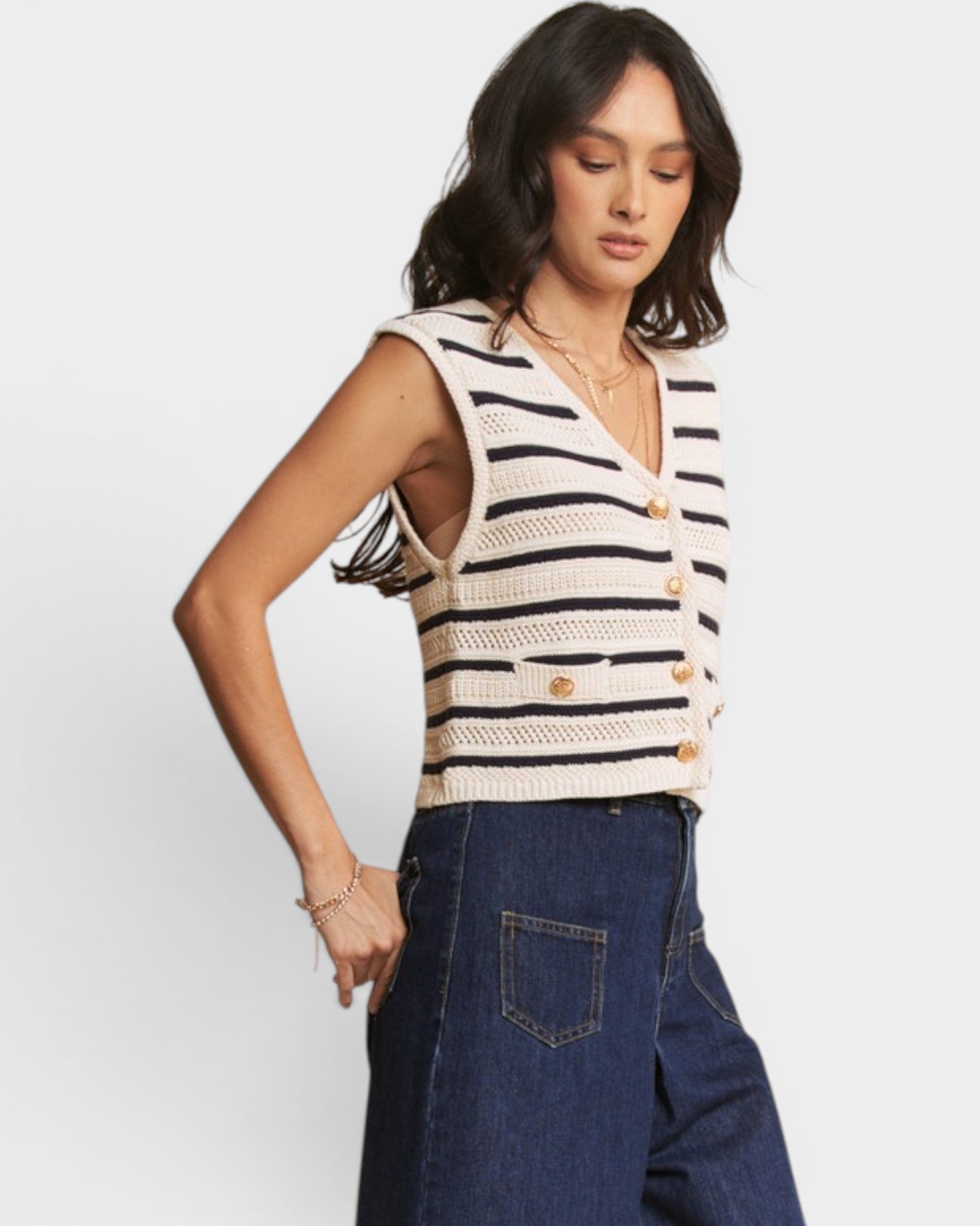 Woman wearing a striped sleeveless top and jeans on a white background
