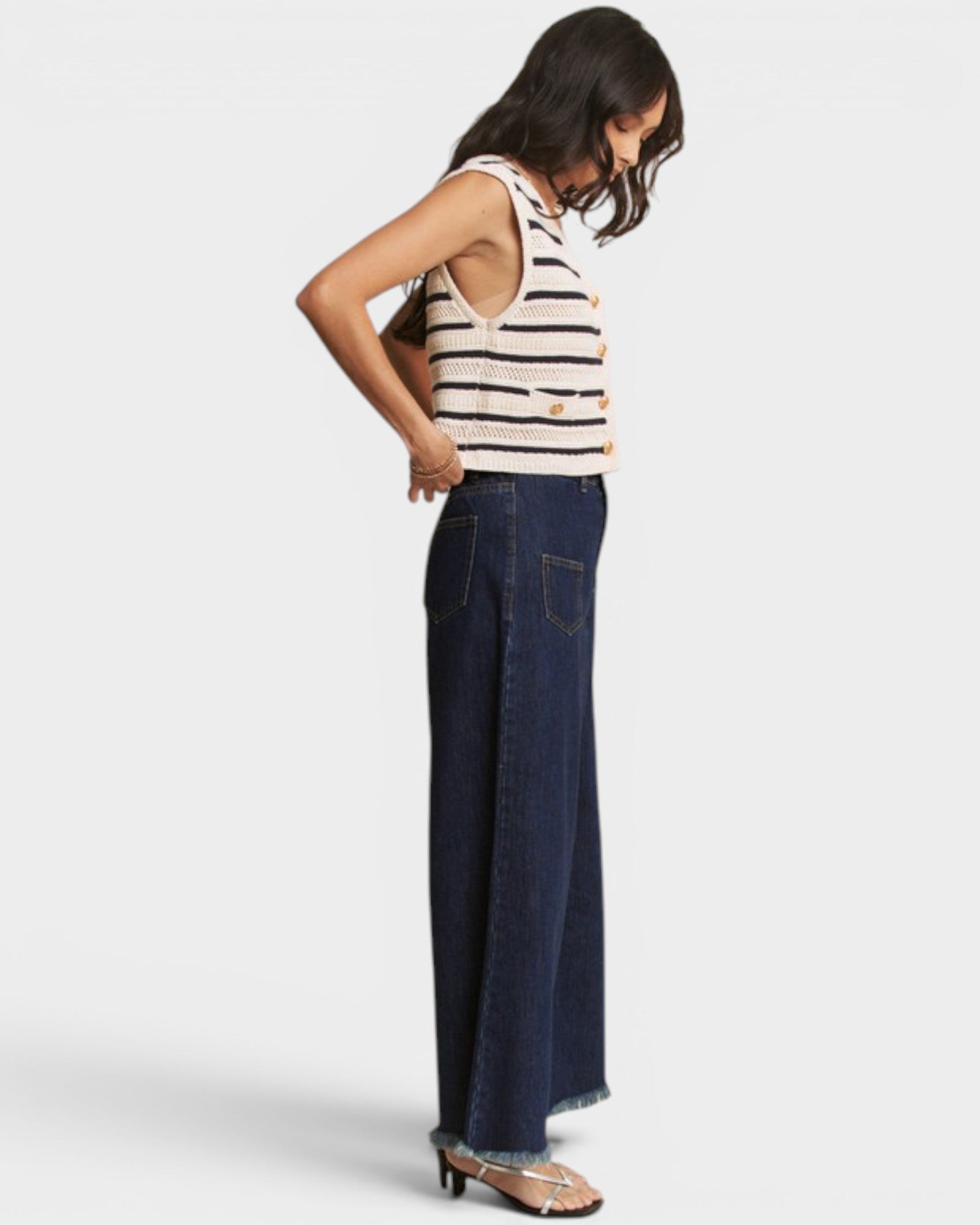Woman wearing a striped top and dark blue jeans on a white background