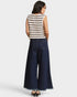 Woman wearing a striped sleeveless top and wide-leg jeans on a white background