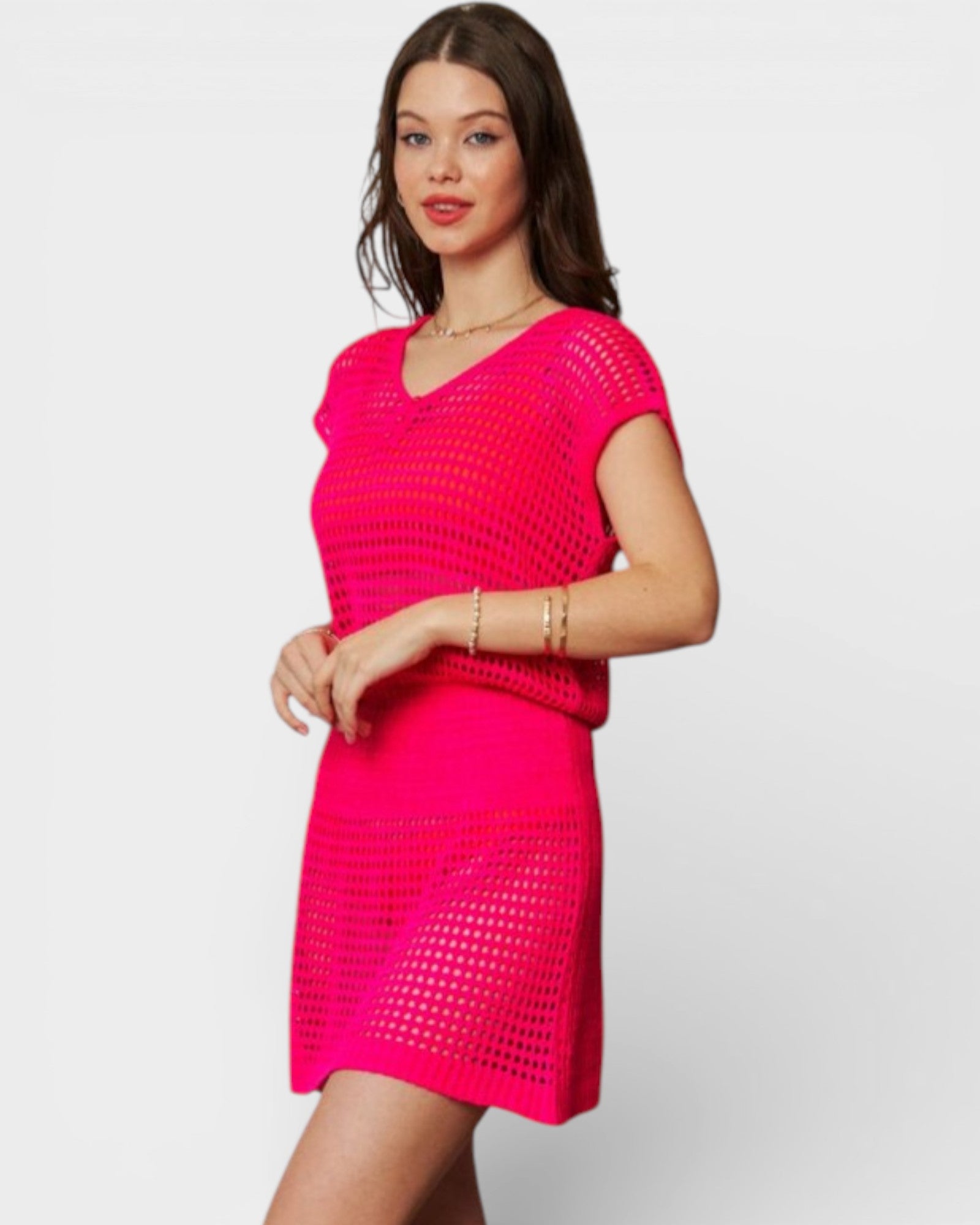 Woman wearing a bright pink crochet dress on a white background