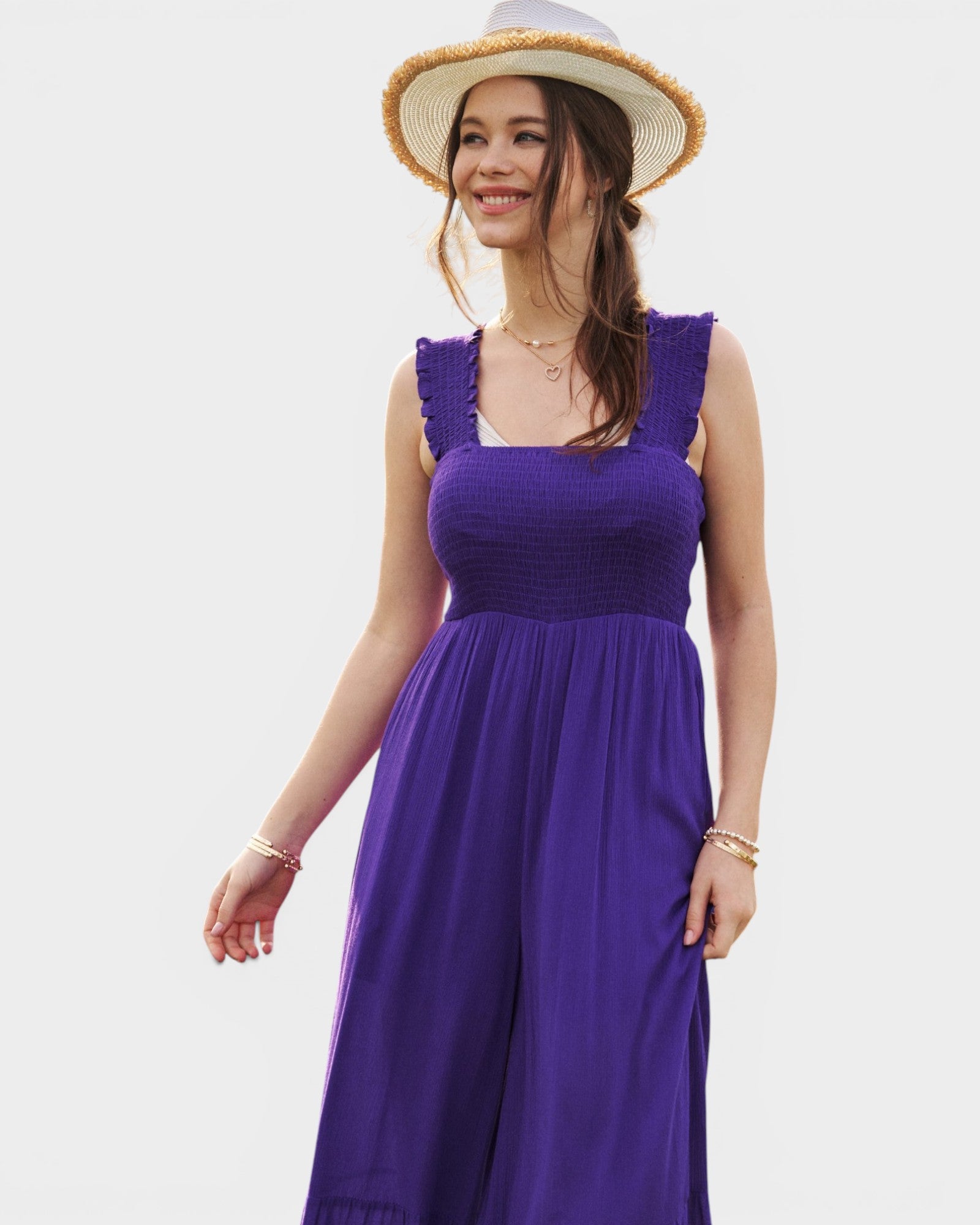Woman wearing a purple dress and straw hat on a white background