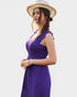 Woman wearing a purple dress and straw hat on a white background