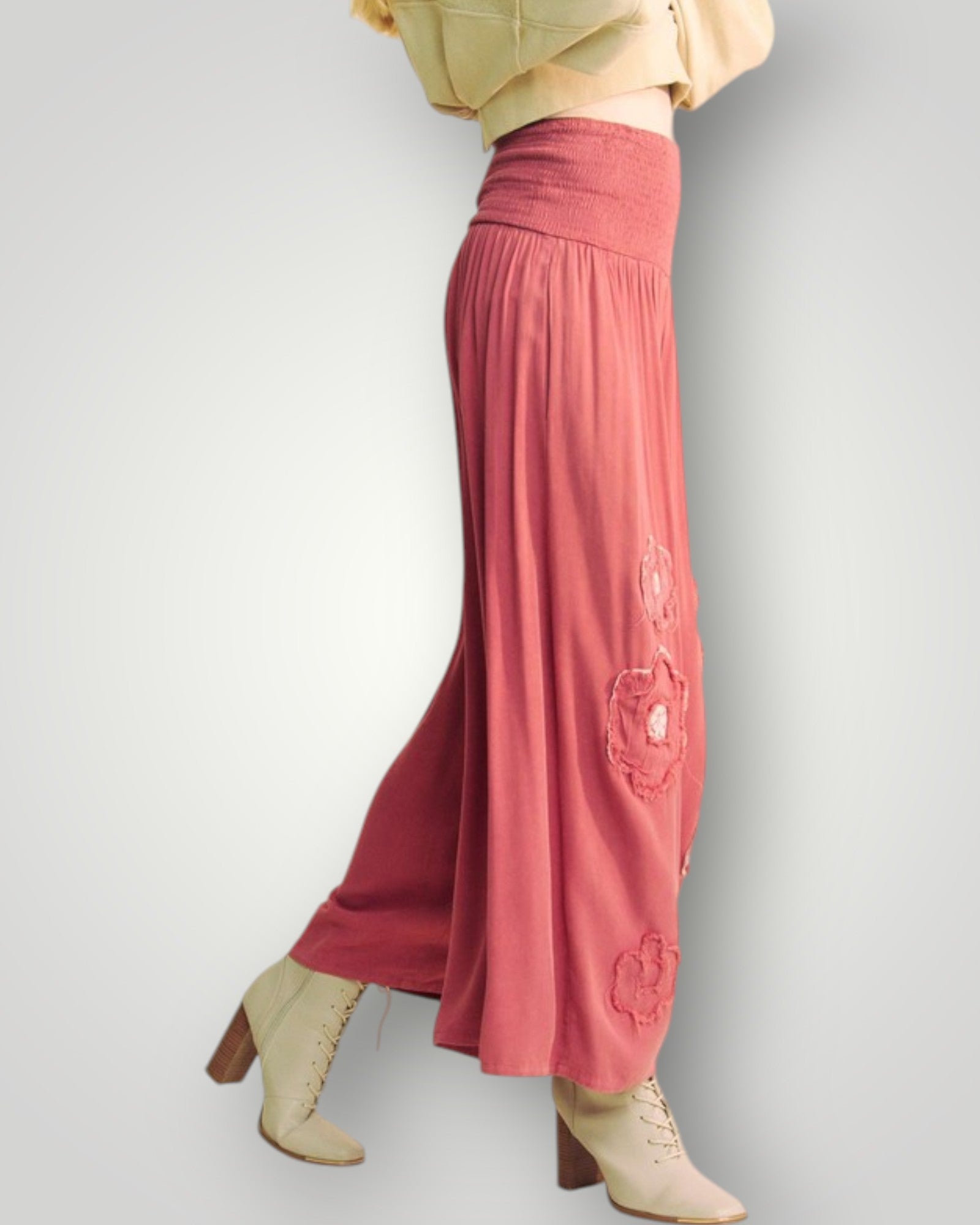 Person wearing pink pants with floral embroidery on a plain background