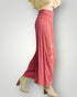 Person wearing pink pants with floral embroidery on a plain background