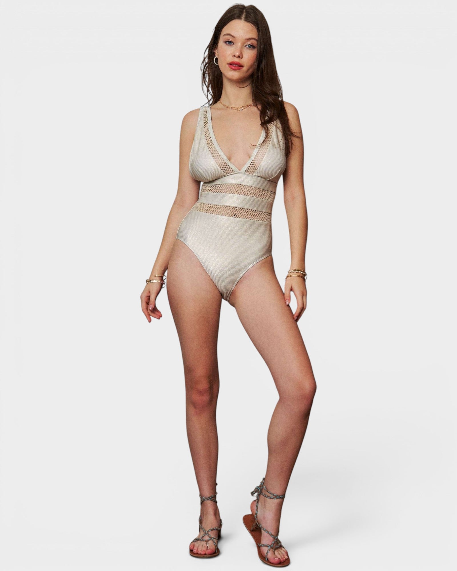 Woman wearing a beige swimsuit with mesh panels on a white background