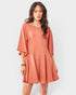 Woman wearing a coral romper on a white background